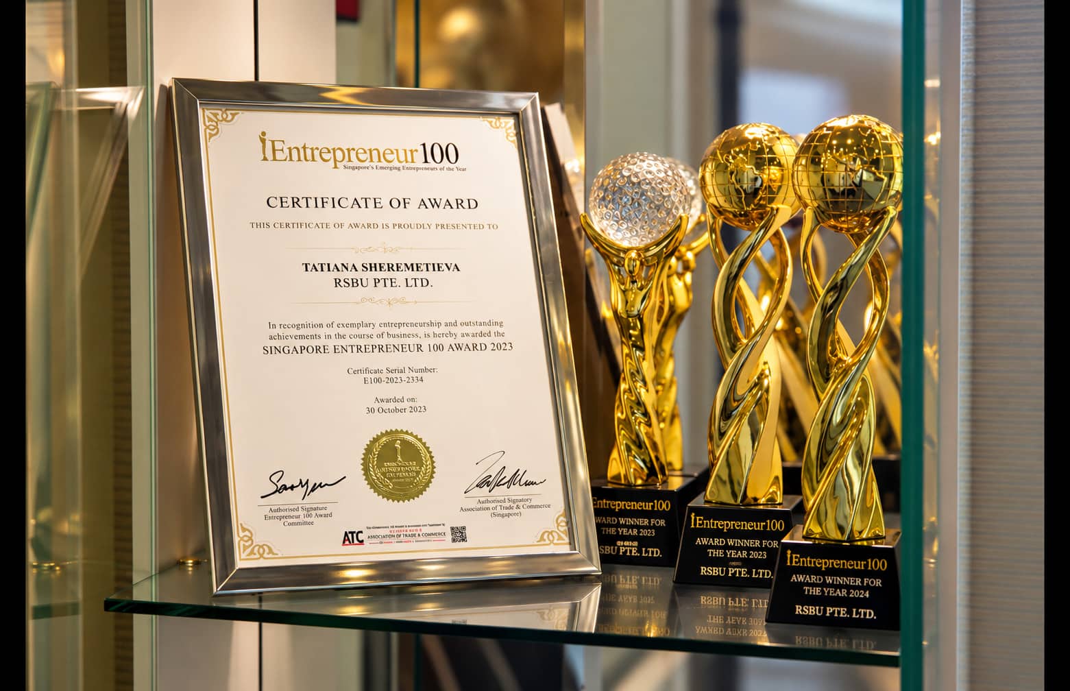 Singapore Entrepreneur 100 Award certificate for Tatiana Sheremetieva with gold trophies